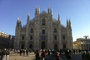 a large building with many people in front with Milan Cathedral in the background