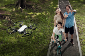 a man woman and boy on a bike and a drone flying