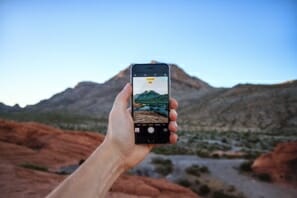 a hand holding a phone with a landscape in the background