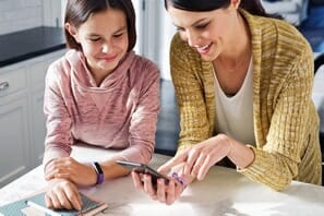 a woman and a girl looking at a phone