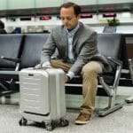 News: SkyValet Carry-On Case a man sitting on a bench with a suitcase