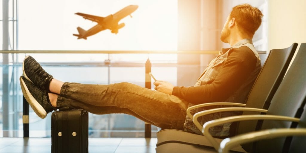 a man sitting in a chair with his feet up looking at an airplane