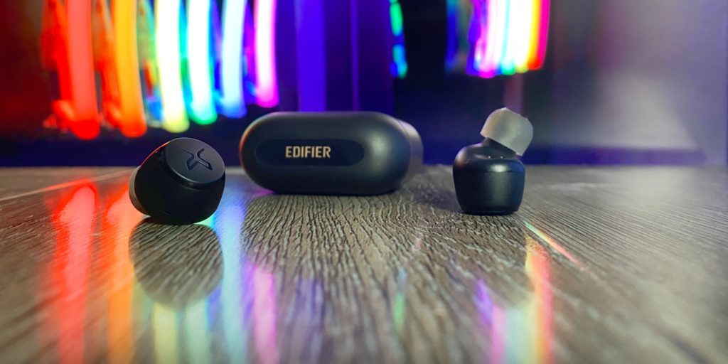 a pair of black wireless earbuds on a wooden surface