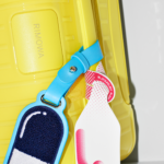 RIMOWA x CHAOS Limited Edition Adds a Drop of Colour to the Iconic Cabin Case a yellow suitcase with a blue tag attached to it