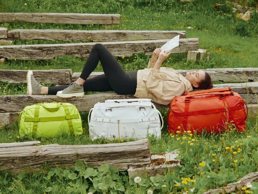a woman lying on a bench with luggage
