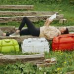 New Away F.A.R Collection Takes you Beyond the Airport Terminal a woman lying on a bench with luggage