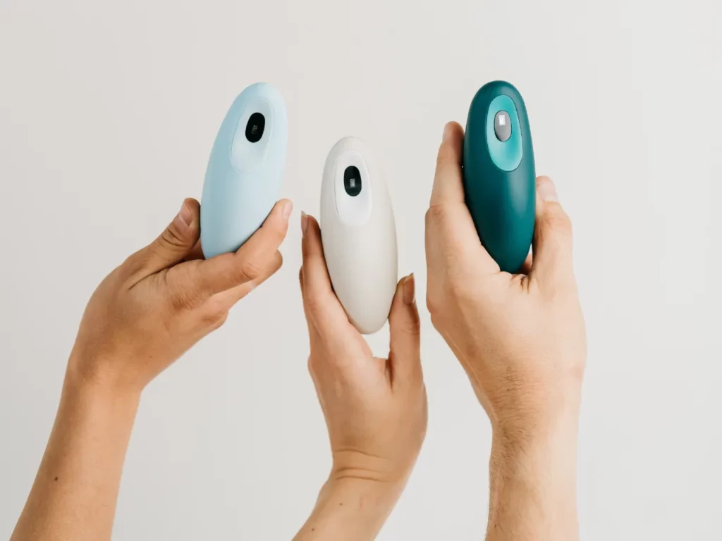 a group of hands holding small objects.  Moonbird colour options.  {Tech} for Travel. https://techfortravel.co.uk