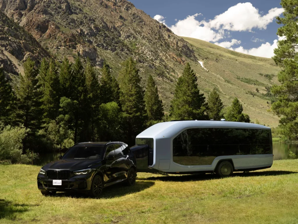 a black car and a bus parked in a grassy area.  CES 2024 News Pebble Flow Electric RV.  {Tech} for Travel. https://techfortravel.co.uk