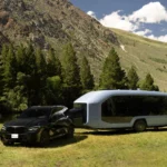CES 2024: Pebble Flow is the Revolutionary Electric RV Redefining Outdoor Adventures a black car and a bus parked in a grassy area. CES 2024 News Pebble Flow Electric RV. {Tech} for Travel. https://techfortravel.co.uk