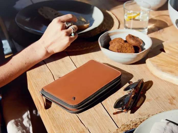 a hand holding a purse and a wallet on a table