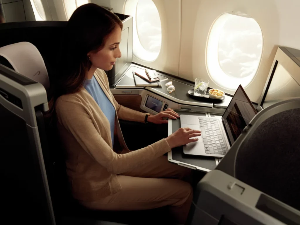 a woman sitting in an airplane using a laptop.  British Airways App.  {Tech} for Travel. https://techfortravel.co.uk