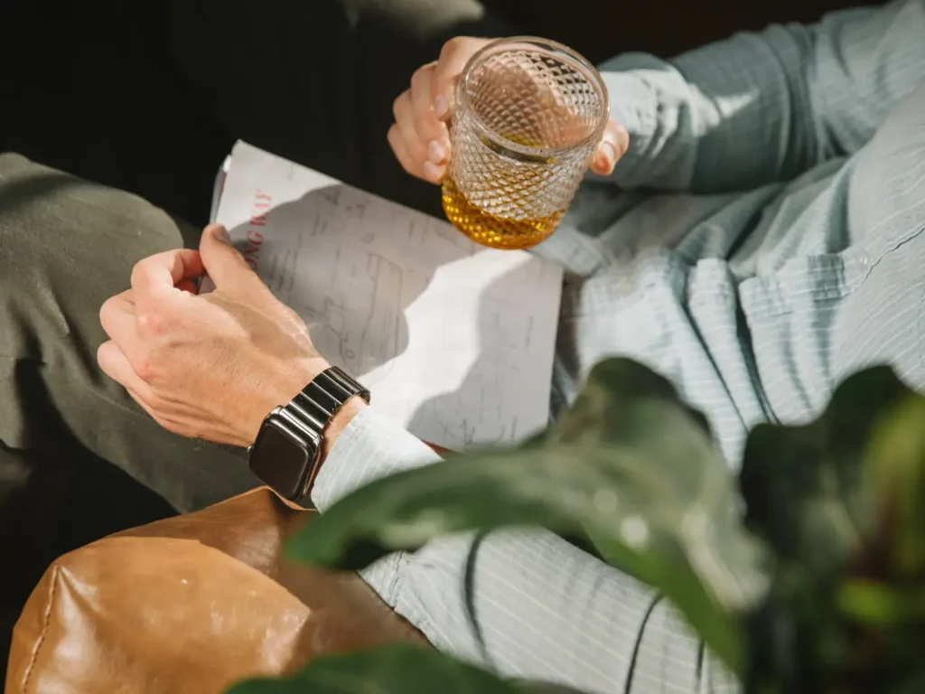 a person holding a glass of liquid. Nomad Goods Titanium Band for Apple Watch Ultra 2.  {Tech} for Travel. https://techfortravel.co.uk