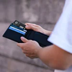 a person holding a wallet with credit cards in it. Rolling Square AirCard Pro