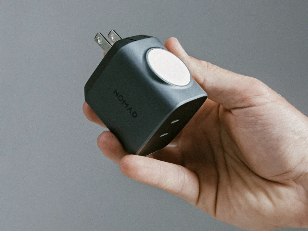 a hand holding a black square device. Apple Watch Edition 65W Power Adaptor. {Tech} for Travel. https://techfortravel.co.uk