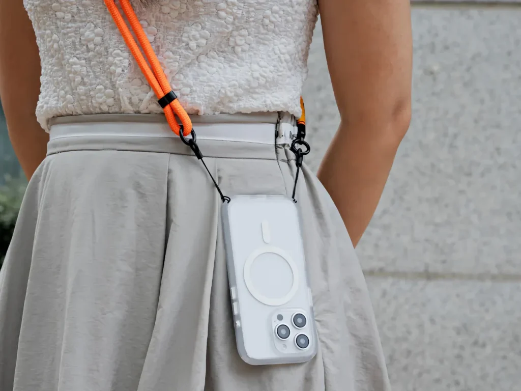 a person wearing a white dress with a phone attached to her waist. Apple iPhone 16. Best Apple iPhone 16 Cases. {Tech} for Travel. https://techfortravel.co.uk