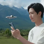 a man holding a phone and looking at a flying drone. DJI Neo