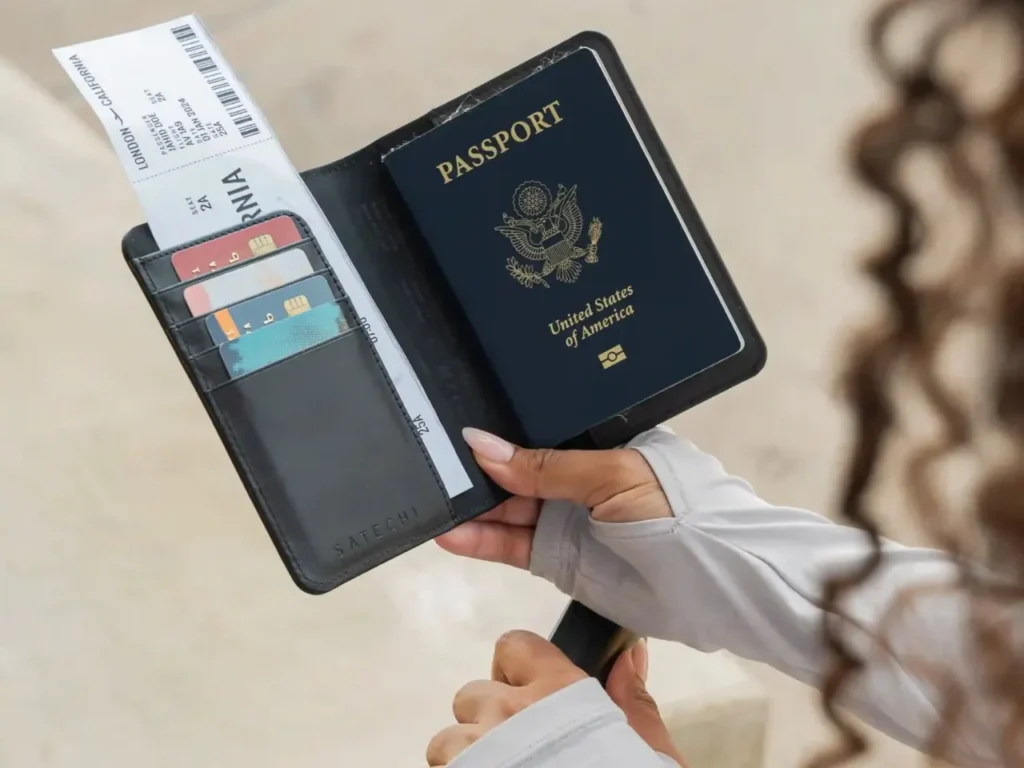 a person holding a passport and a few tickets. Satechi Passport Cover with Find My.  {Tech} for Travel. https://techfortravel.co.uk