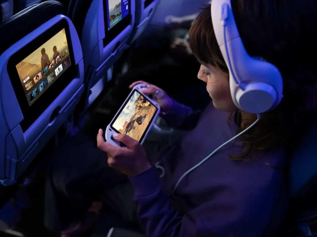 a woman sitting in an airplane with headphones and a device. United Starlink Wi-Fi launch 2025. United Starlink Wi-Fi.  {Tech} for Travel. https://techfortravel.co.uk