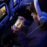United Starlink Wi-Fi Launch will Bring Free In-Flight Internet a woman sitting in an airplane with headphones and a device. United Starlink Wi-Fi launch 2025