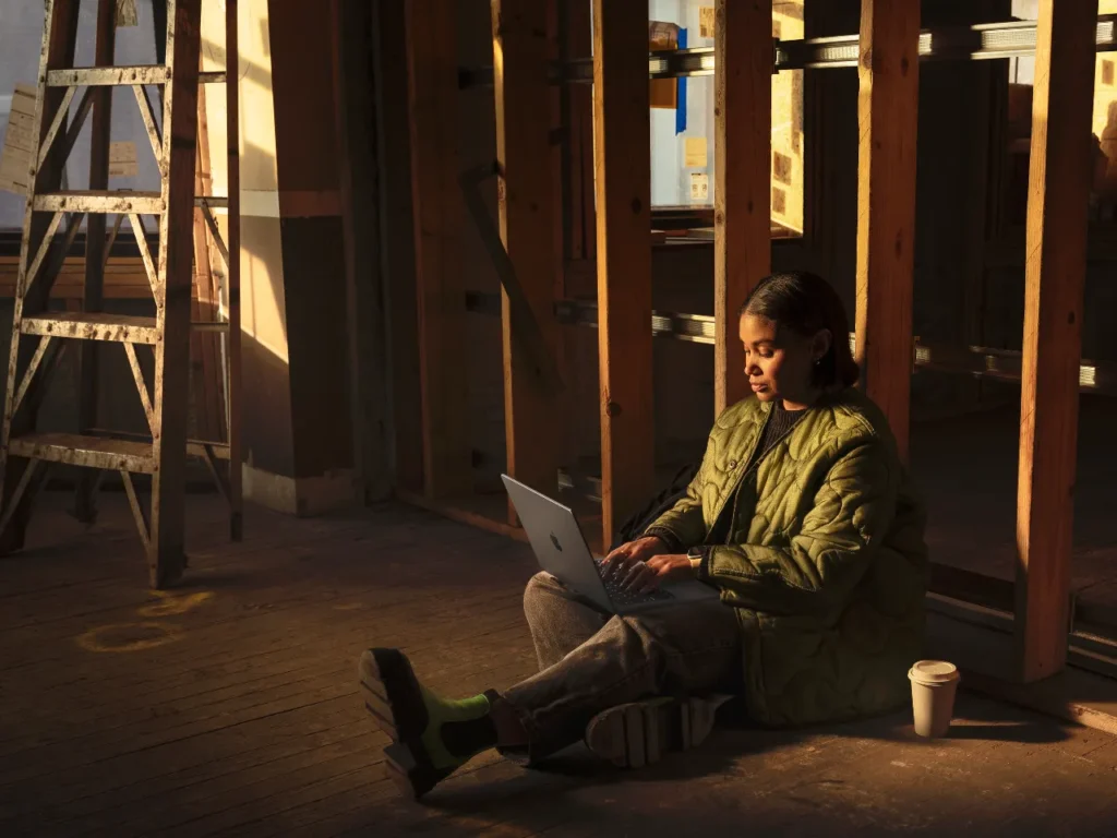 a woman sitting on the floor with a laptop. Apple MacBook Pro M4 Specifications.  {Tech} for Travel. https://techfortravel.co.uk