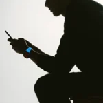 Nomad Goods Limited Edition Icy Blue Band is Cool, Bold & Glowing a silhouette of a man holding a phone. Nomad Goods Limited Edition Icy Blue Glow