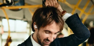 CES 2025 News: OpenRock X A New Era in Open Ear Design a man with a beard wearing a white shirt and black jacket. OpenRock X headphones. {Tech} for Travel. https://techfortravel.co.uk