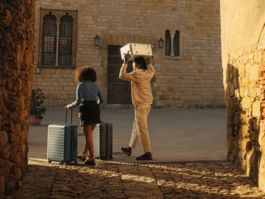 a man and woman carrying luggage. Away suitcases