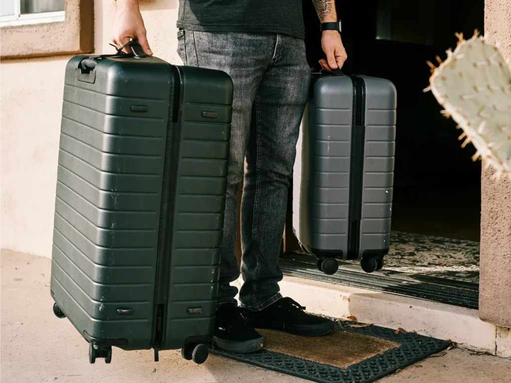 a person holding luggage in front of a door. Suitcases and Carry On.  {Tech} for Travel. https://techfortravel.co.uk