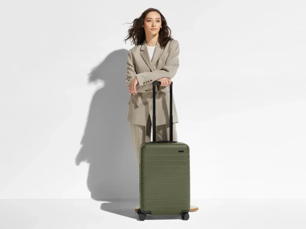 a woman in a suit with a suitcase. Away Bigger Carry-On. Best Carry-On Cases 2025. {Tech} for Travel. https://techfortravel.co.uk