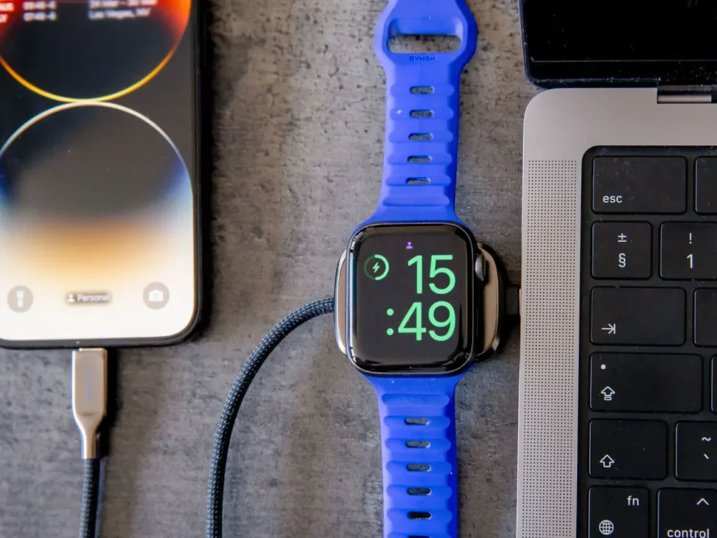 a blue smart watch with a blue strap next to a laptop and a phone. Nomad Goods Universal Cable for Apple Watch Review.  {Tech} for Travel. https://techfortravel.co.uk