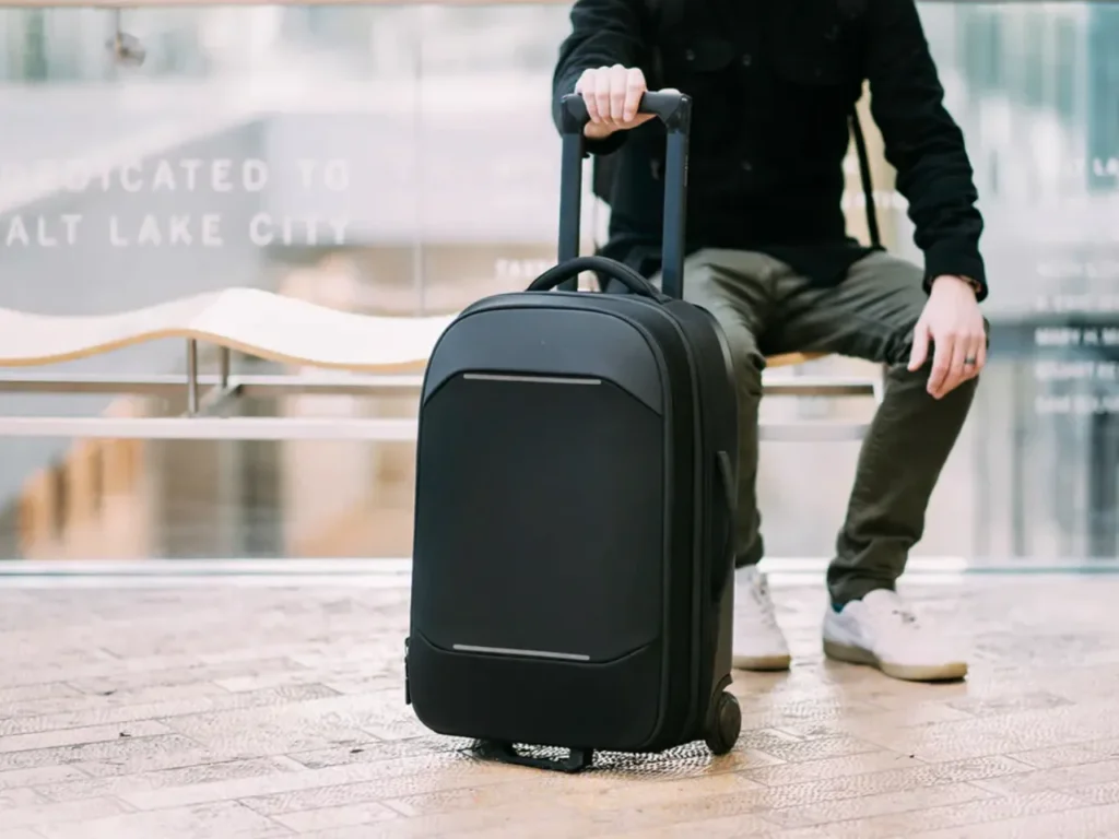 a person sitting on a bench with a suitcase. Best Carry-On Cases 2025. {Tech} for Travel. https://techfortravel.co.uk