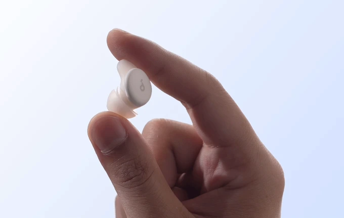1612a4875da62784577e3d8c7ec55a39_original – {Tech} for Travel a person holding a white earbud. Soundcore Sleep A30. Healthy Travel Gadgets. {Tech} for Travel. https://techfortravel.co.uk