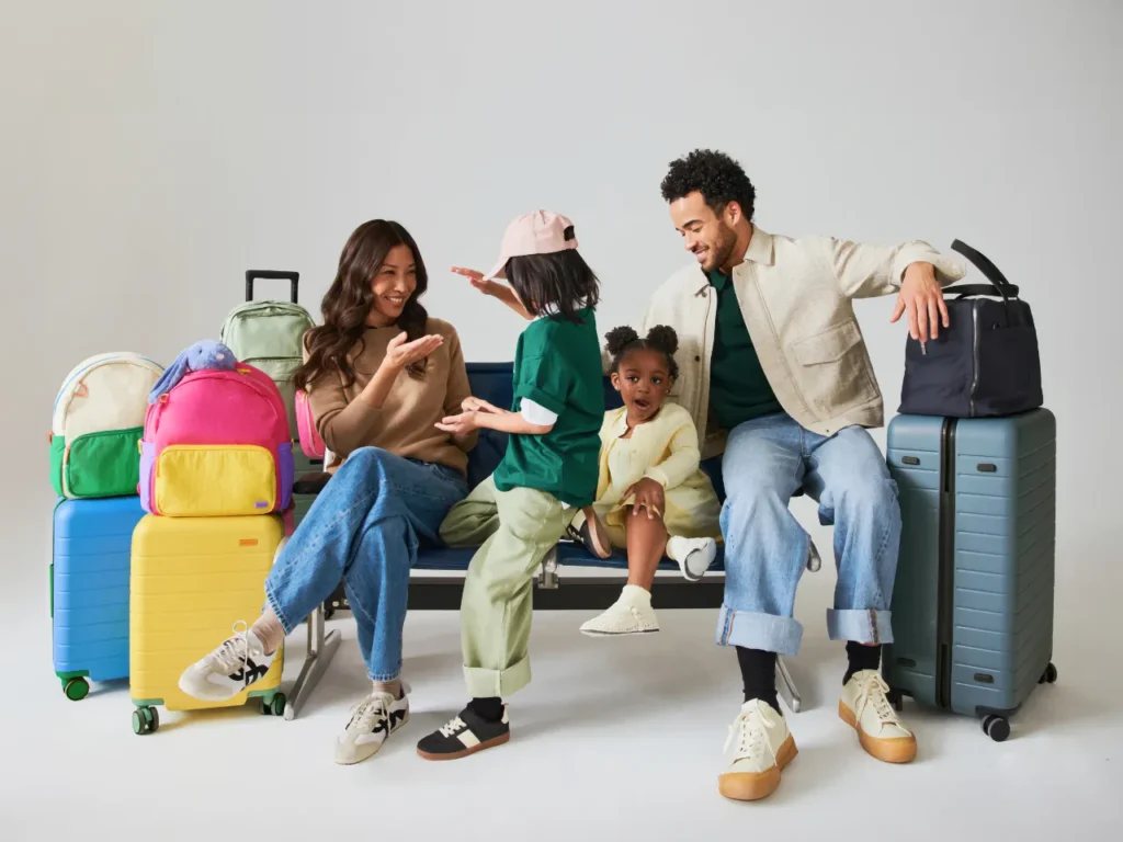 Away Kids Collection Hero – {Tech} for Travel a family sitting on a bench with luggage. Away Kids Collection. {Tech} for Travel. https://techfortravel.co.uk