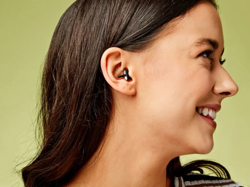 Flare Audio Calmer Pro – {Tech} for Travel a woman smiling with earbuds. Flare Audio Calmer Pro. Healthy Travel Gadgets. {Tech} for Travel. https://techfortravel.co.uk