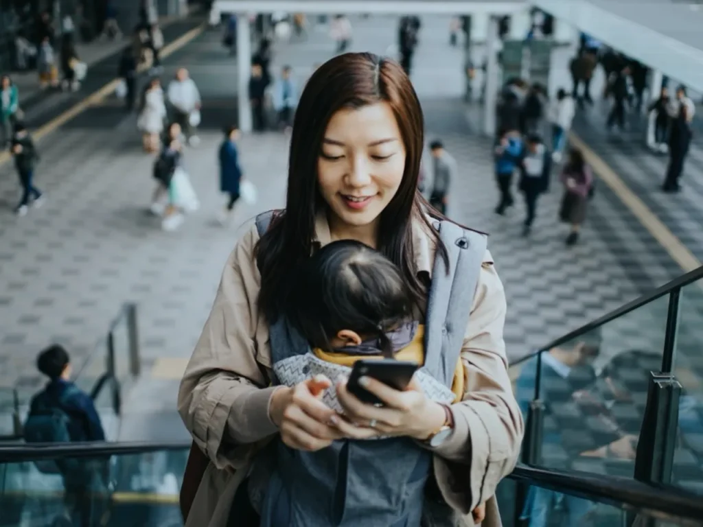 a woman holding a baby on a cellphone. Fly Delta App version 7. {Tech} for Travel. https://techfortravel.co.uk