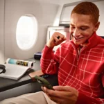 Lufthansa Wi-Fi Adds Free Chat on All Intercontinental Routes a man sitting on an airplane looking at a cellphone. Lufthansa Wi-Fi Free Messaging. {Tech} for Travel. https://techfortravel.co.uk