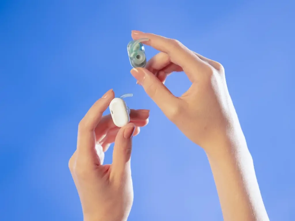 Natura AI HumanPods – {Tech} for Travel hands holding a hearing aid. Natura AI HumanPods. {Tech} for Travel. https://techfortravel.co.uk