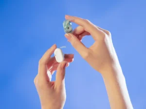 hands holding a hearing aid. Natura AI HumanPods. {Tech} for Travel. https://techfortravel.co.uk
