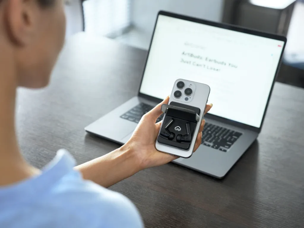 a person holding a phone and a laptop. Komutr MagSafe earbuds. IFA 2025 News. {Tech} for Travel. https://techfortravel.co.uk