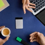 IFA 2025: The Slim, Smart, and Sharp New Plaud Note Pro a person's hands holding a cup of coffee and a laptop. Plaud Note Pro. IFA 2025 news. {Tech} for Travel. https://techfortravel.co.uk