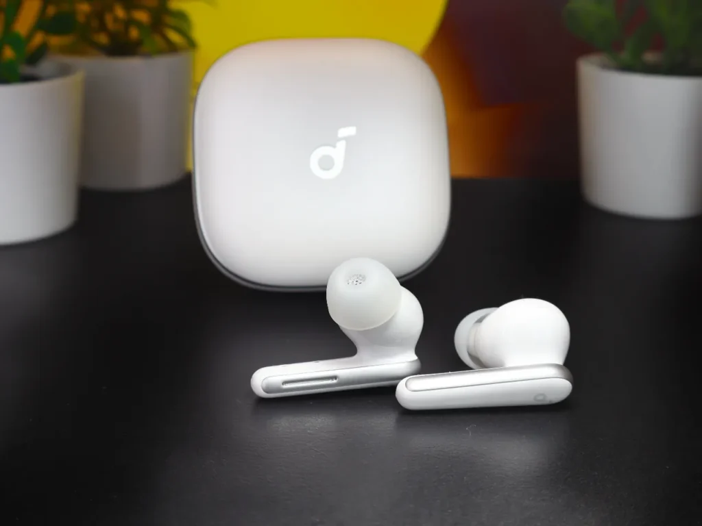 Soundcore Liberty 5 Earbuds stems – {Tech} for Travel a pair of white earbuds on a black surface. Soundcore Liberty 5 review. {Tech} for Travel. https://techfortravel.co.uk