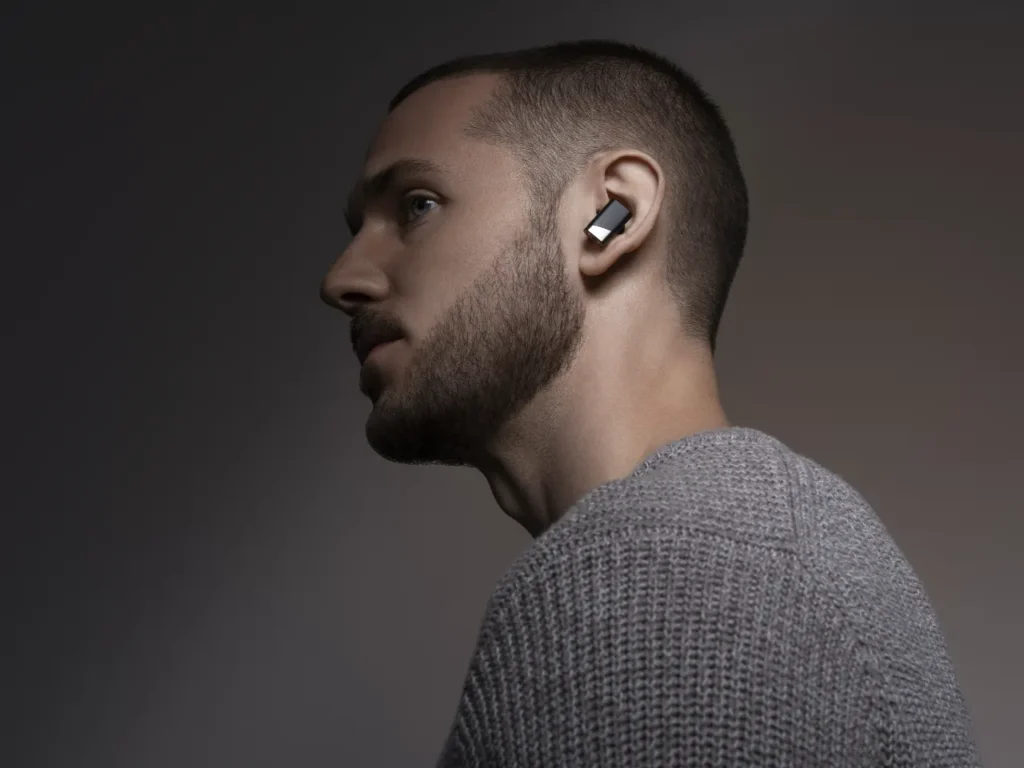 Status Pro X Earbuds Model – {Tech} for Travel a man wearing a grey sweater. IFA 2025 news. Status Pro X Earbuds. {Tech} for Travel. https://techfortravel.co.uk