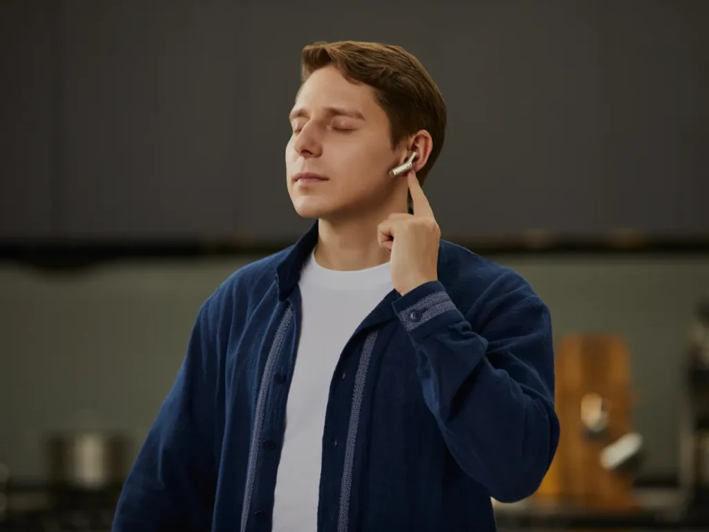 Timekettle W4 AI Translator Earbuds Hero – {Tech} for Travel a man with his eyes closed holding his earbuds to his ear. Timekettle W4 AI Translator Earbuds. {Tech} for Travel. https://techfortravel.co.uk