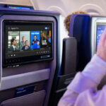 Apple TV+ shows hit the skies with United Airlines a man sitting in an airplane with a television screen. United Airlines Apple TV. {Tech} for Travel. https://techfortravel.co.uk