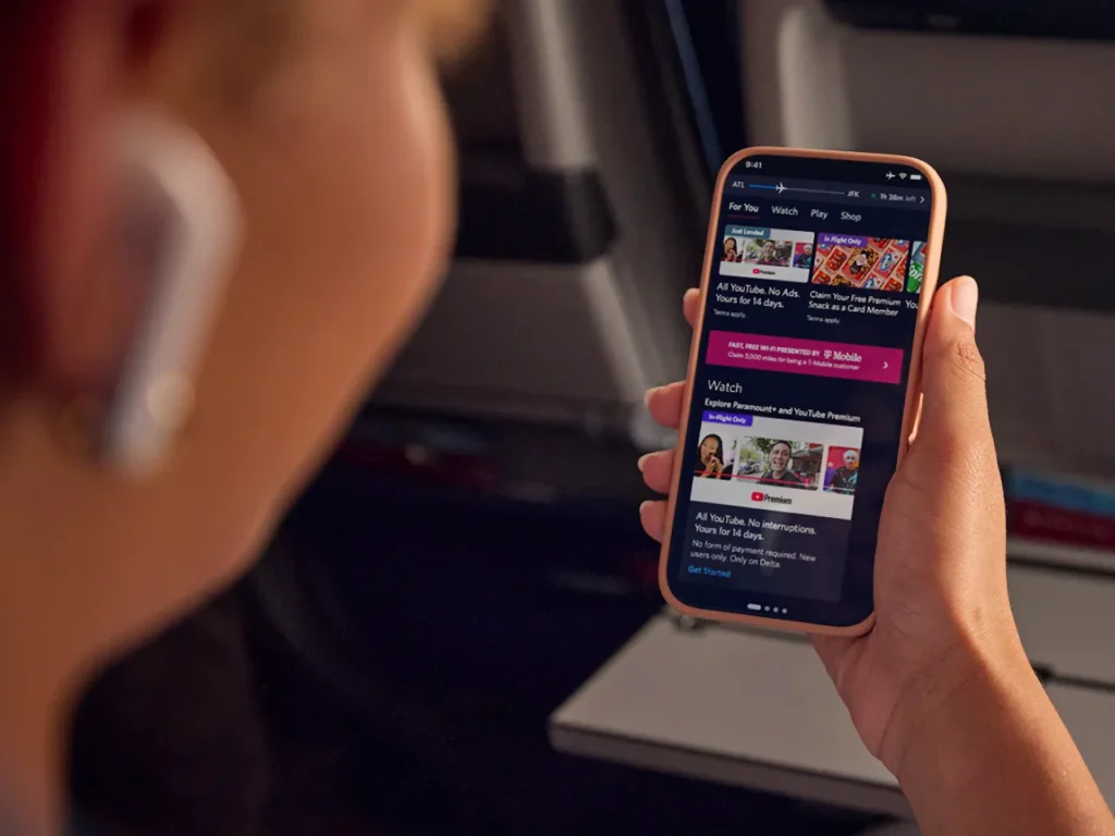 a person holding a cellphone. Delta Inflight YouTube.  {Tech} for Travel. https://techfortravel.co.uk