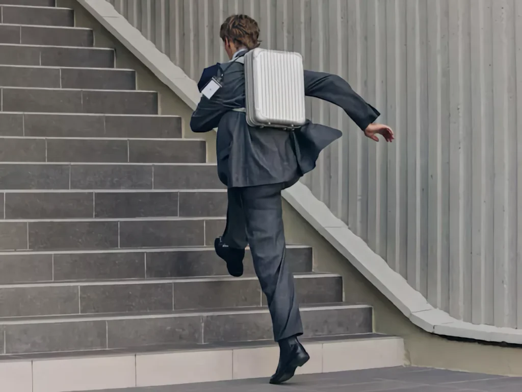 a man running up stairs with a briefcase. RIMOWA Original Backpack. {Tech} for Travel. https://techfortravel.co.uk