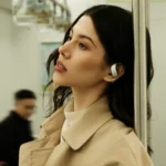 IFA 2025: Clear sound and instant recording with viaim OpenNote Earphones a woman with earbuds leaning against a pole. viaim opennote earphones. {Tech} for Travel. https://techfortravel.co.uk