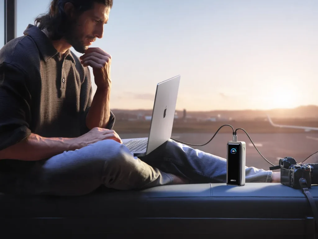 Anker Prime Power Bank Airport – {Tech} for Travel a man sitting on a car with a laptop. Anker Prime. {Tech} for Travel. https://techfortravel.co.uk