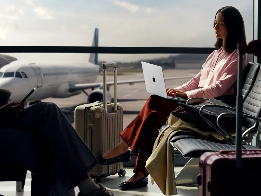 Apple MacBook Pro M5 Airport – {Tech} for Travel a woman sitting in an airport with a laptop. Apple MacBook Pro M5. {Tech} for Travel. https://techfortravel.co.uk
