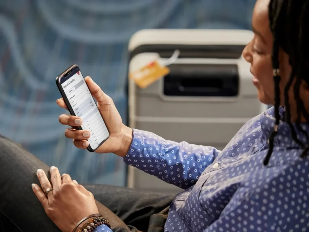 Fly Delta App In Use – {Tech} for Travel a woman holding a cell phone. Delta App. {Tech} for Travel. https://techfortravel.co.uk